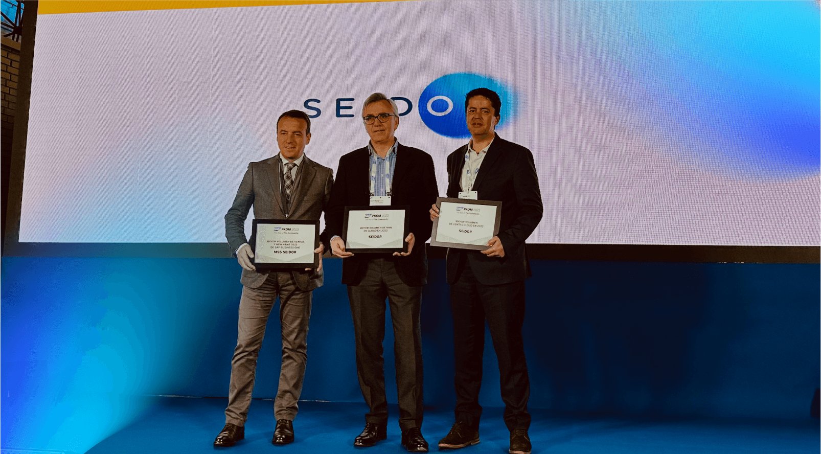 tres personas en un escenario mostrando un premio